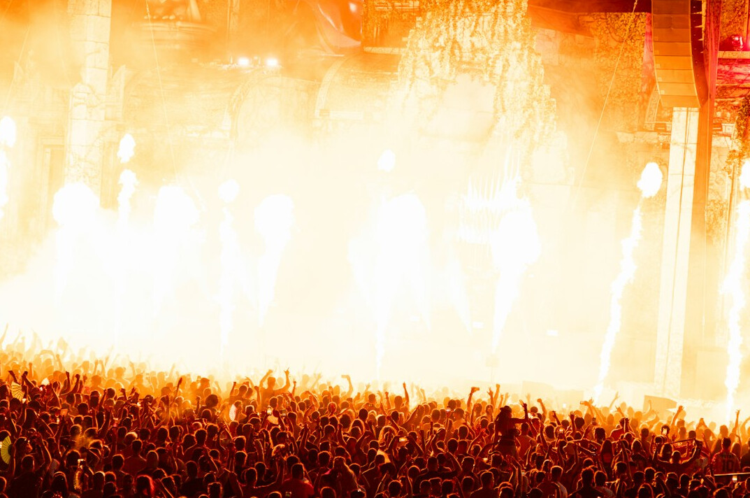 Music festival crowd under stage lights at sunset